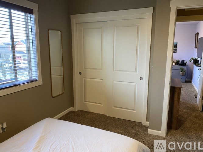 A white door is in a room with a window and a bed.