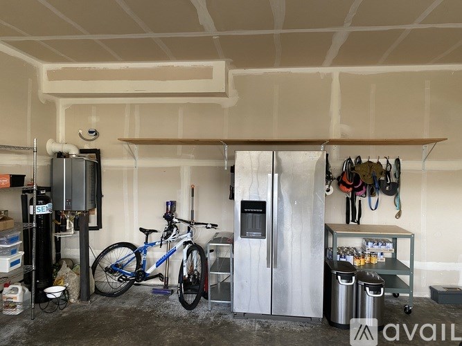 A room with a bicycle, a fridge, and a shelf with various items.