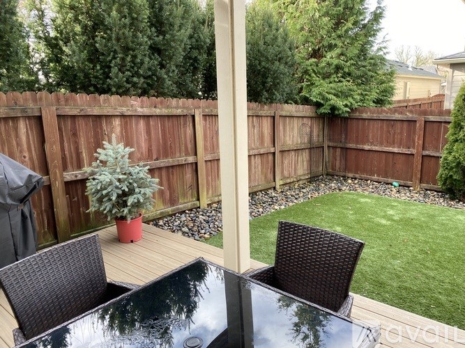 A backyard with a wooden fence and a glass table.