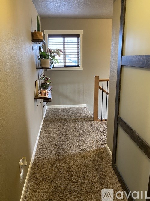 A hallway with a carpeted floor and a window with blinds.