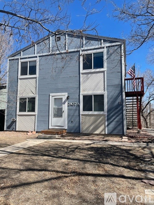 A two-story house with a grey exterior and a red deck.