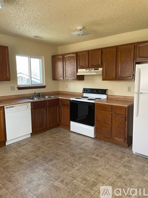 A kitchen with brown cabinets and white appliances.