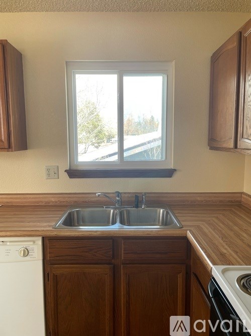 A kitchen with wooden cabinets and a window overlooking a street.