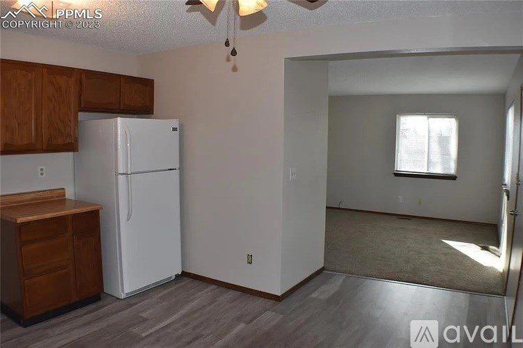 A kitchen with a white refrigerator and wooden cabinets.