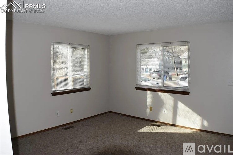 A room with two windows and carpeted floor.