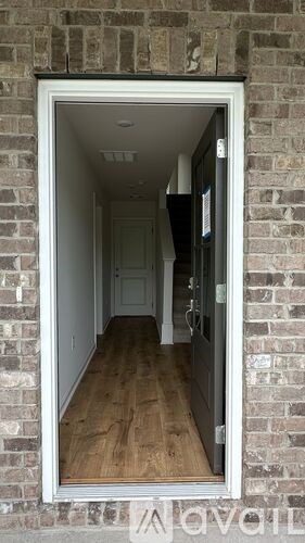 A white doorway with a brick wall on the outside and a hallway on the inside.