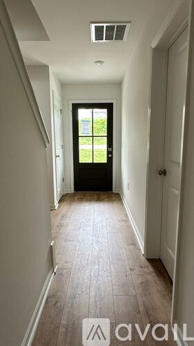 A hallway with a black door and a window.