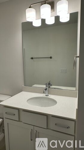 A bathroom with a sink, mirror, and lights.