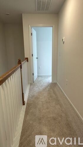 A hallway with a carpeted floor and a door at the end.