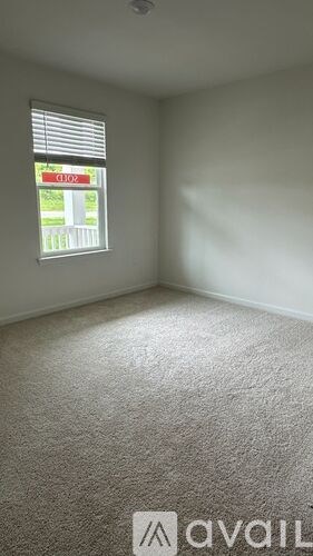 A carpeted room with a window showing a sign for a store.