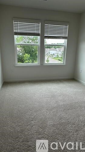 A room with a carpeted floor and a window with blinds.