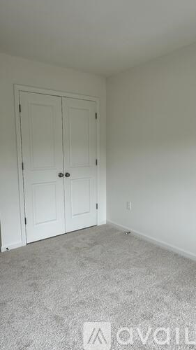 A room with a carpeted floor and a white door.