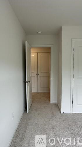 A hallway with a carpeted floor and white walls.