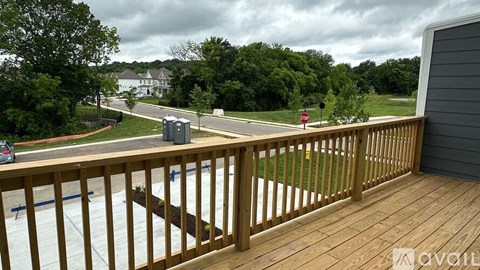 A deck with a railing overlooks a street with a stop sign.