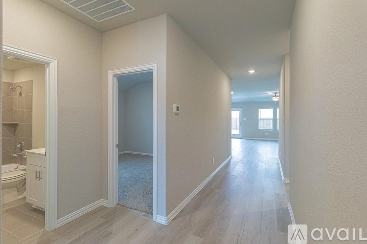 A long hallway with a bathroom on the left and a bedroom on the right.