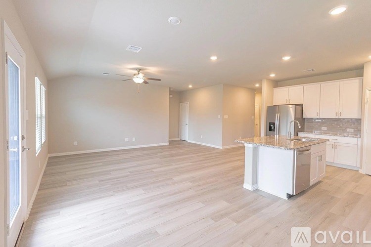 A spacious kitchen and living room with white cabinets and a wooden floor.