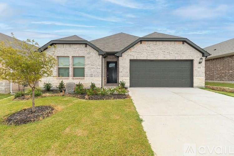 A house with a garage and a tree in front.