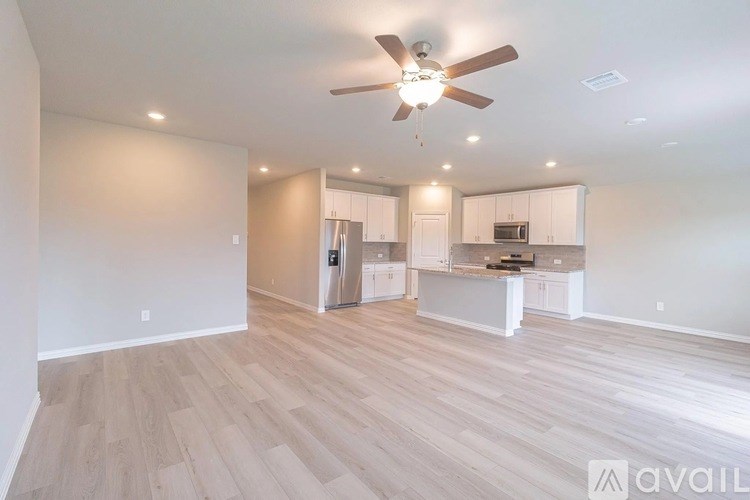 A spacious room with a ceiling fan and lighting fixtures.