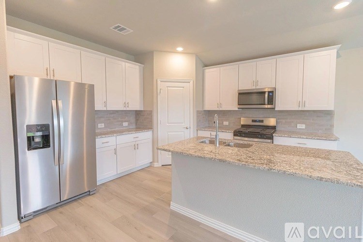 A kitchen with a refrigerator, microwave, and oven.