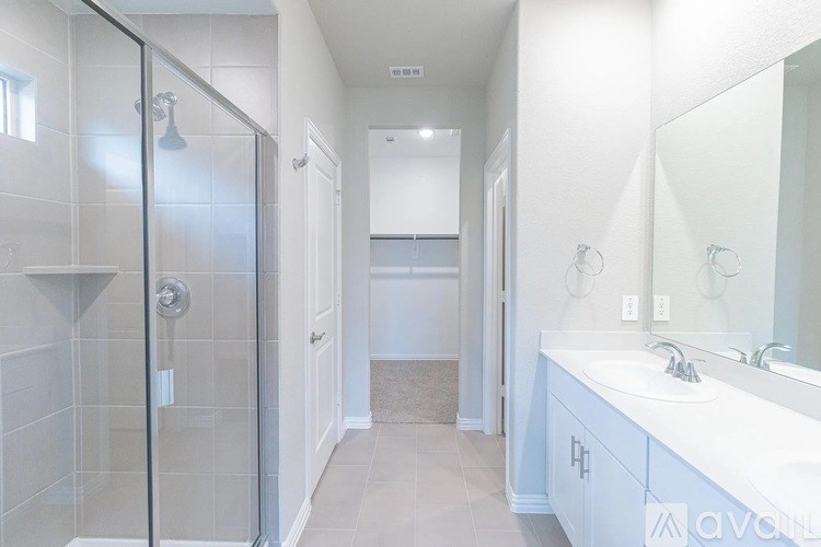 A bathroom with a walk-in shower, double sink vanity, and a large mirror.