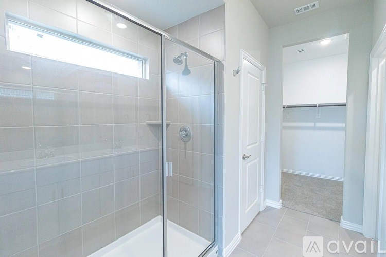 A bathroom with a glass shower door and a white bathtub.