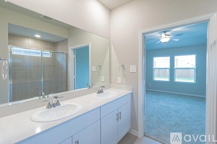 A bathroom with a large mirror, two sinks, and a blue door.