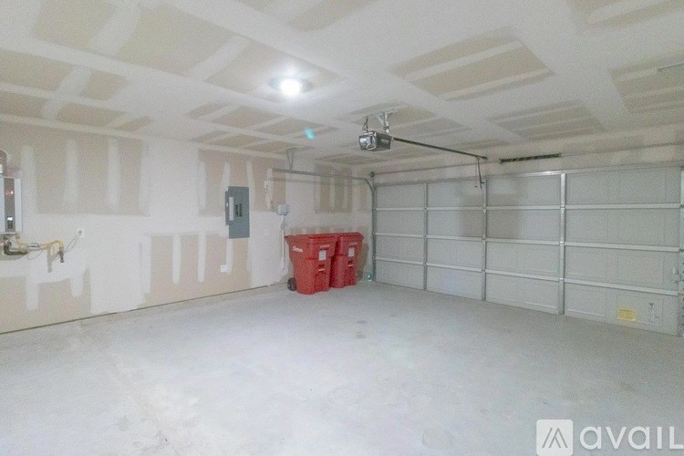 A large empty garage with a red bin and a hanging light fixture.