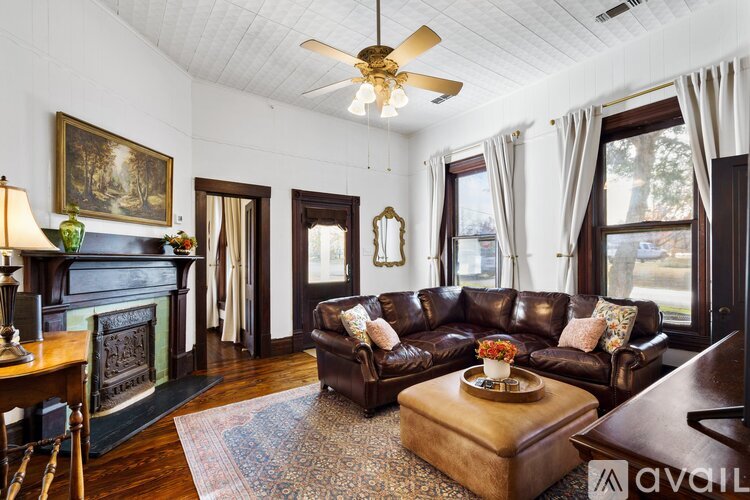 A living room with a brown leather couch and a fireplace.