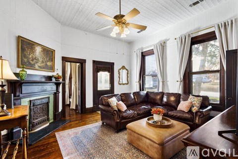 A living room with a brown leather couch and a fireplace.