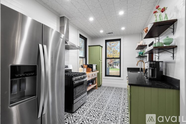 A modern kitchen with a stainless steel refrigerator and black and white tiled floor.
