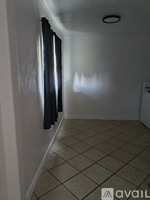 A room with a tiled floor and a window with curtains.
