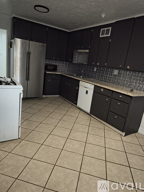 A kitchen with black cabinets and a white refrigerator.