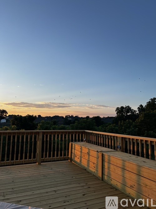 A deck with a railing and a view of the sky and trees.