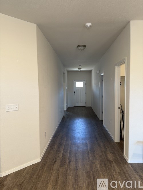 A long hallway with wood floors and white walls.