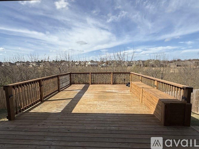 A wooden deck with a bench and a view of a residential area.