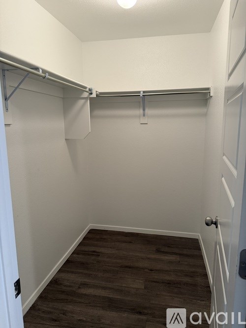 A small, empty room with a wooden floor and white walls.