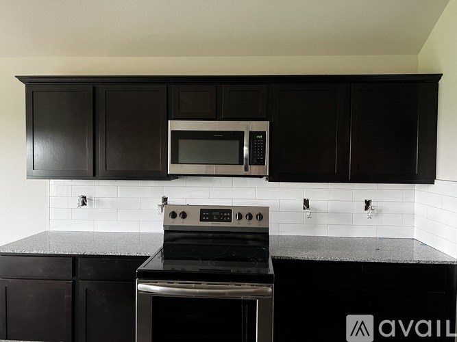 A kitchen with black cabinets and a stainless steel oven.