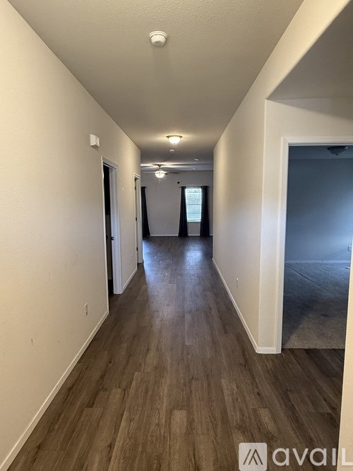 A long hallway with wood flooring and white walls.