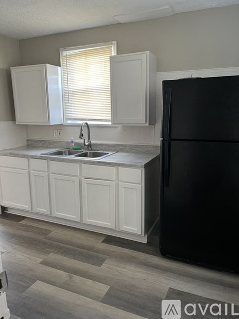 A kitchen with a black refrigerator and white cabinets.