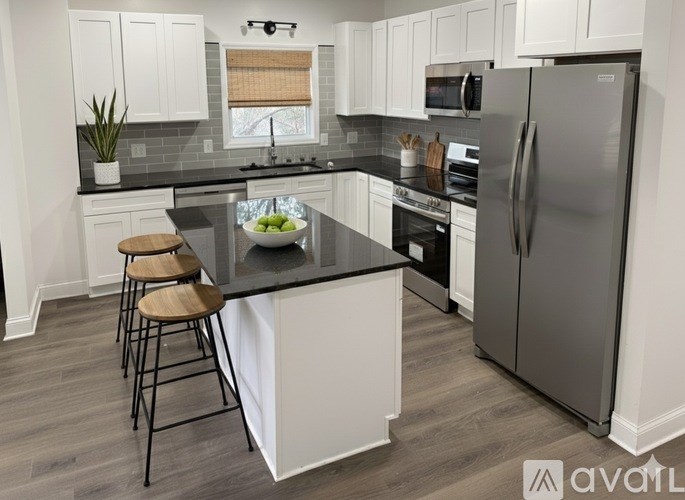 A kitchen with a black countertop and a refrigerator.