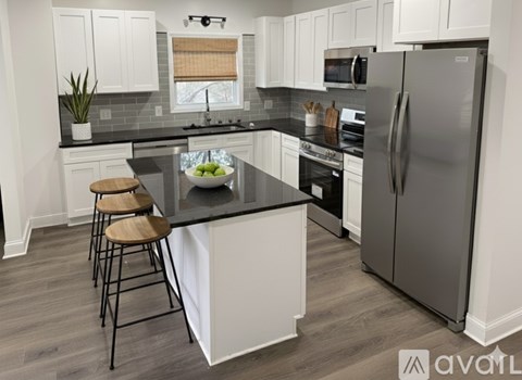 A kitchen with a black countertop and a refrigerator.