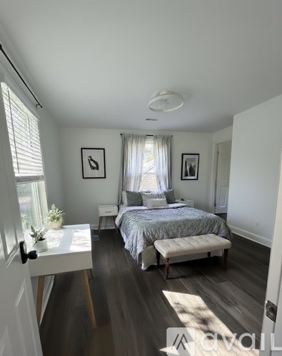 A bedroom with a bed, nightstand, and window.