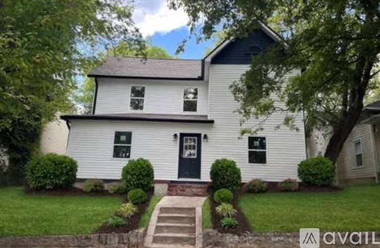 A white house with a black front door and steps leading to it.