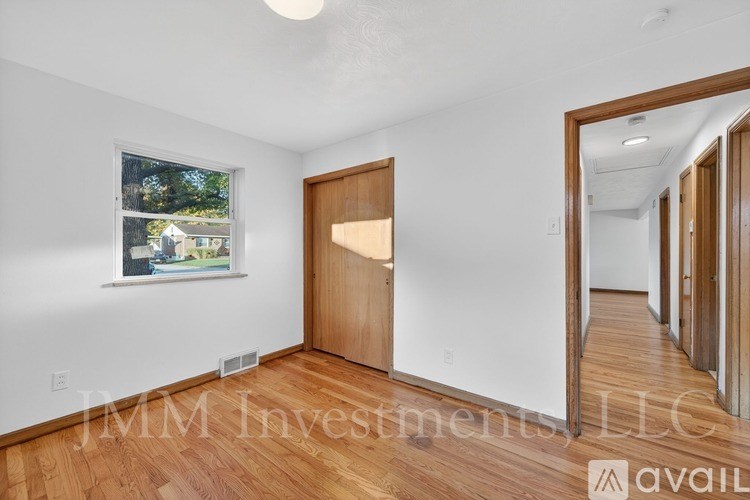 A room with wooden floors and a door leading to another room.