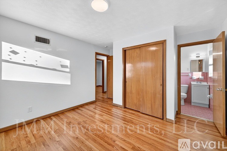 A room with wooden floors and a white wall with a poster on it.