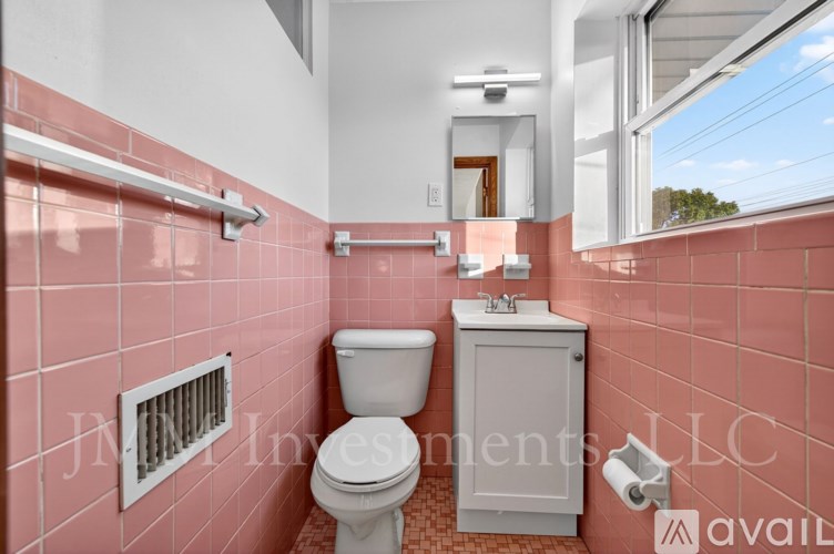 A bathroom with pink tiles and a white toilet.