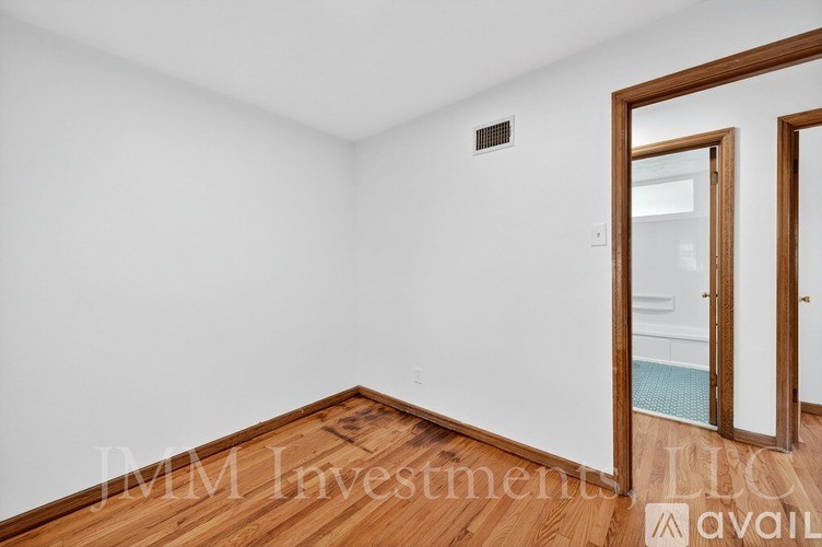 A room with a wooden floor and a white wall with a door on the right side.