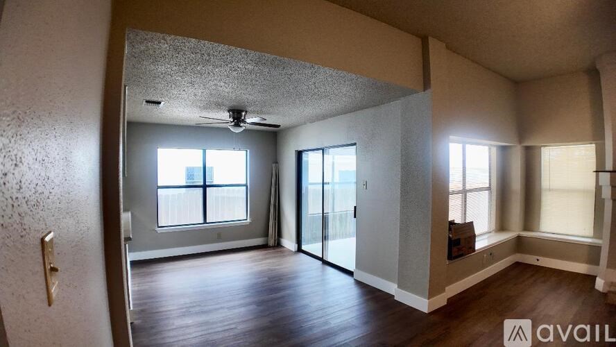 A room with a ceiling fan and sliding glass doors.