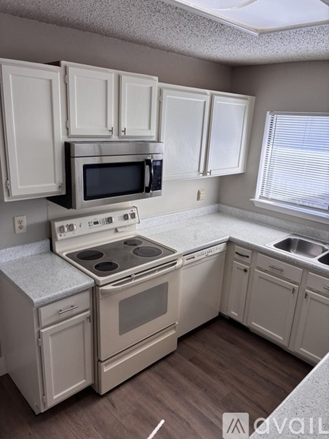 A kitchen with white cabinets and appliances.