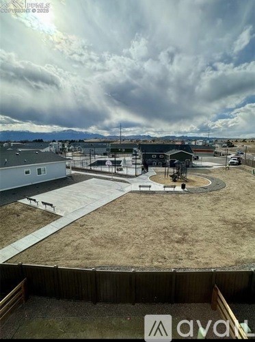 A view from a rooftop of a building with a circular patio and a car parked in the driveway.